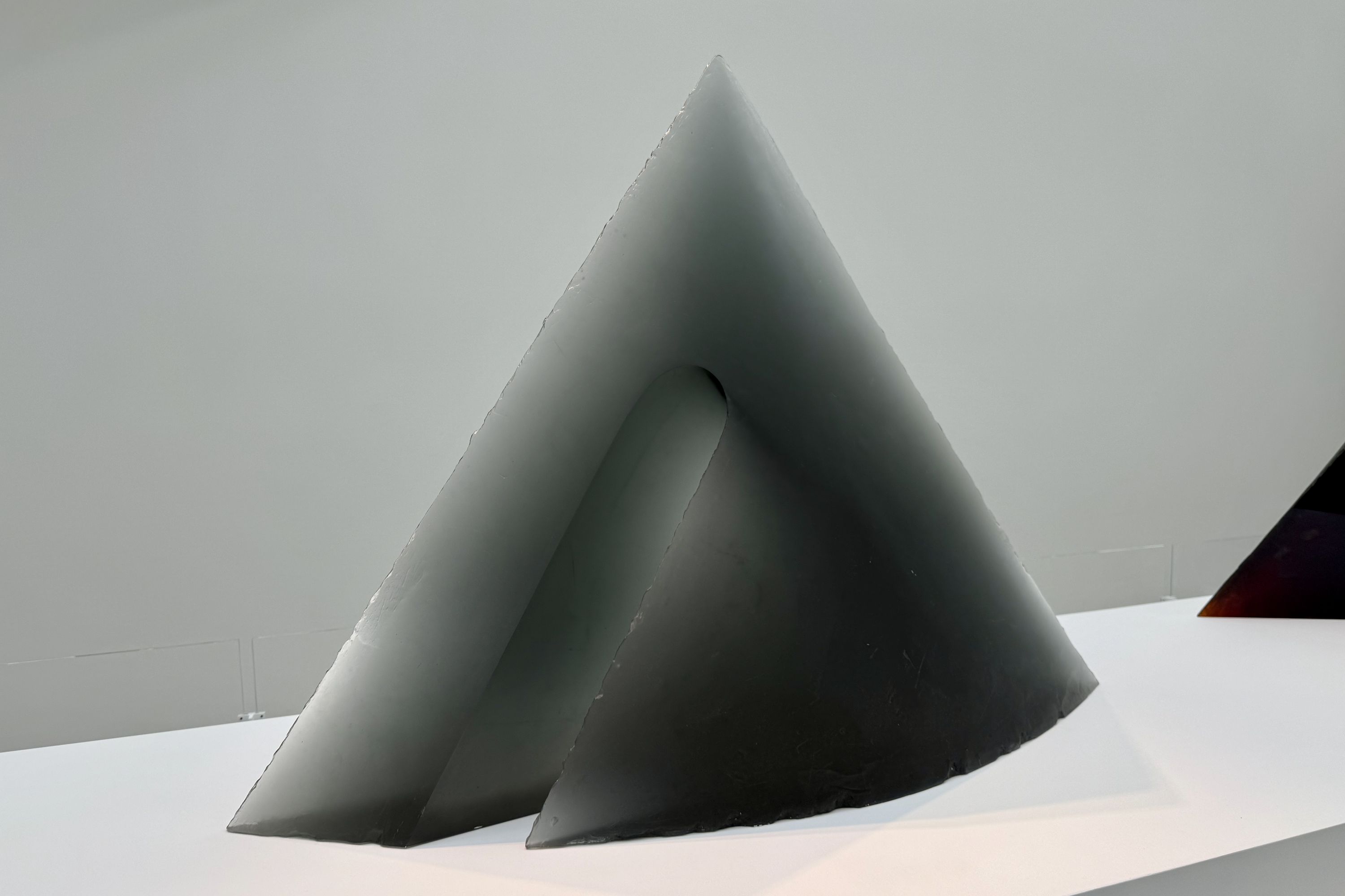 A large, translucent dark gray cast glass sculpture titled 